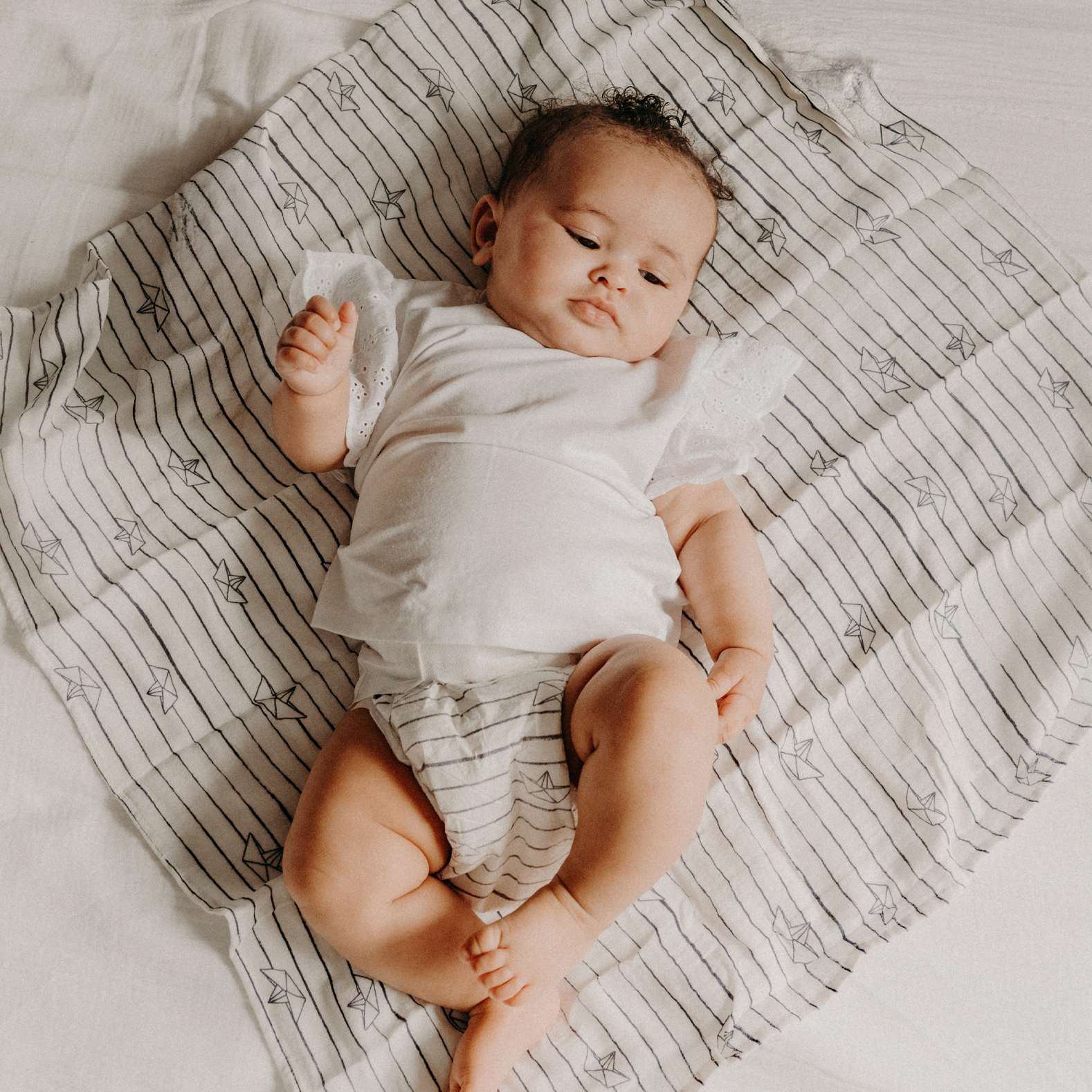 Bébé allongé sur un lange, en couche JOONE testée sous contrôle dermatologique pour les peaux sensibles