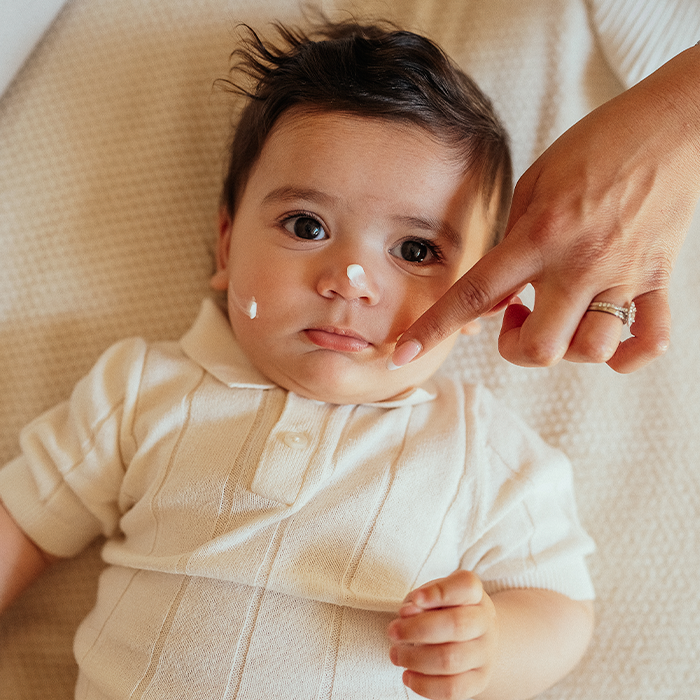 Parent appliquant une crème hydratante sur la peau d'un nouveau-né après le bain