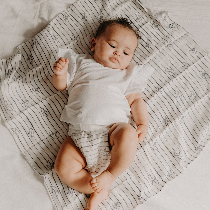 Bébé allongé sur un lange, en couche JOONE testée sous contrôle dermatologique pour les peaux sensibles
