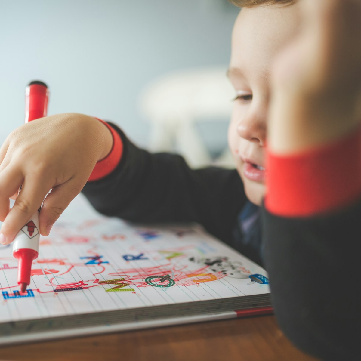 Un jeune enfant dessine au feutre sur une feuille de papier